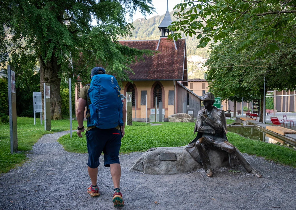 Caminhante diante da estátua de Sherlock Holmes em Meiringen