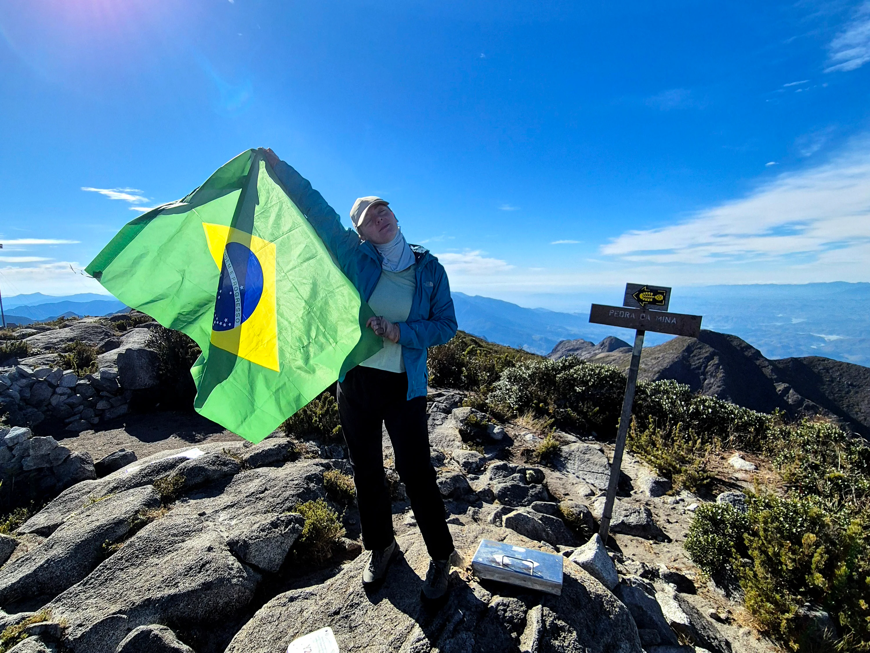 Bia segura a bandeira do Brasil no cume da Pedra da Mina durante a travessia da Serra Fina