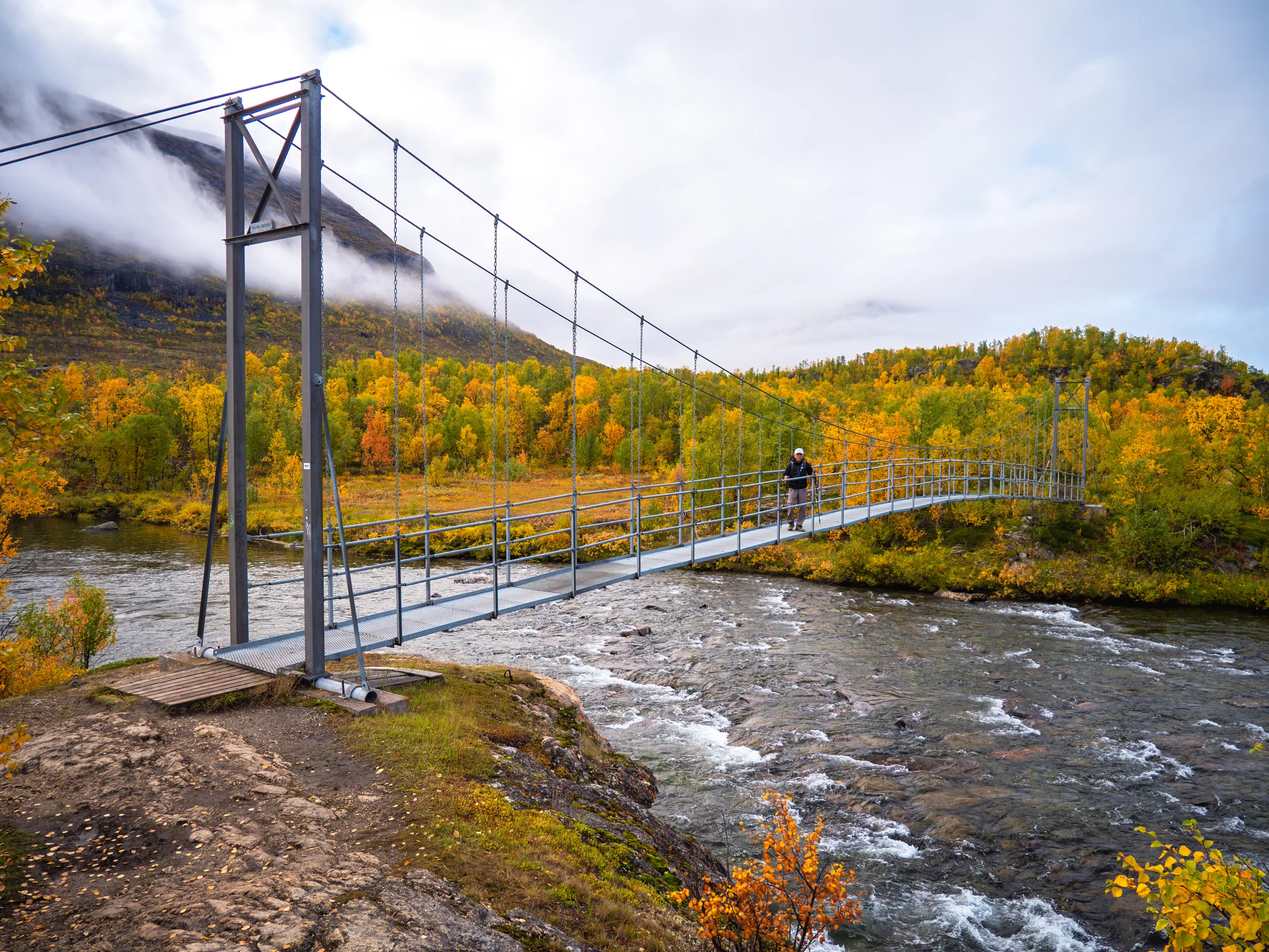 Uma ponte suspensa conecta as margens de um rio na Kungsleden.