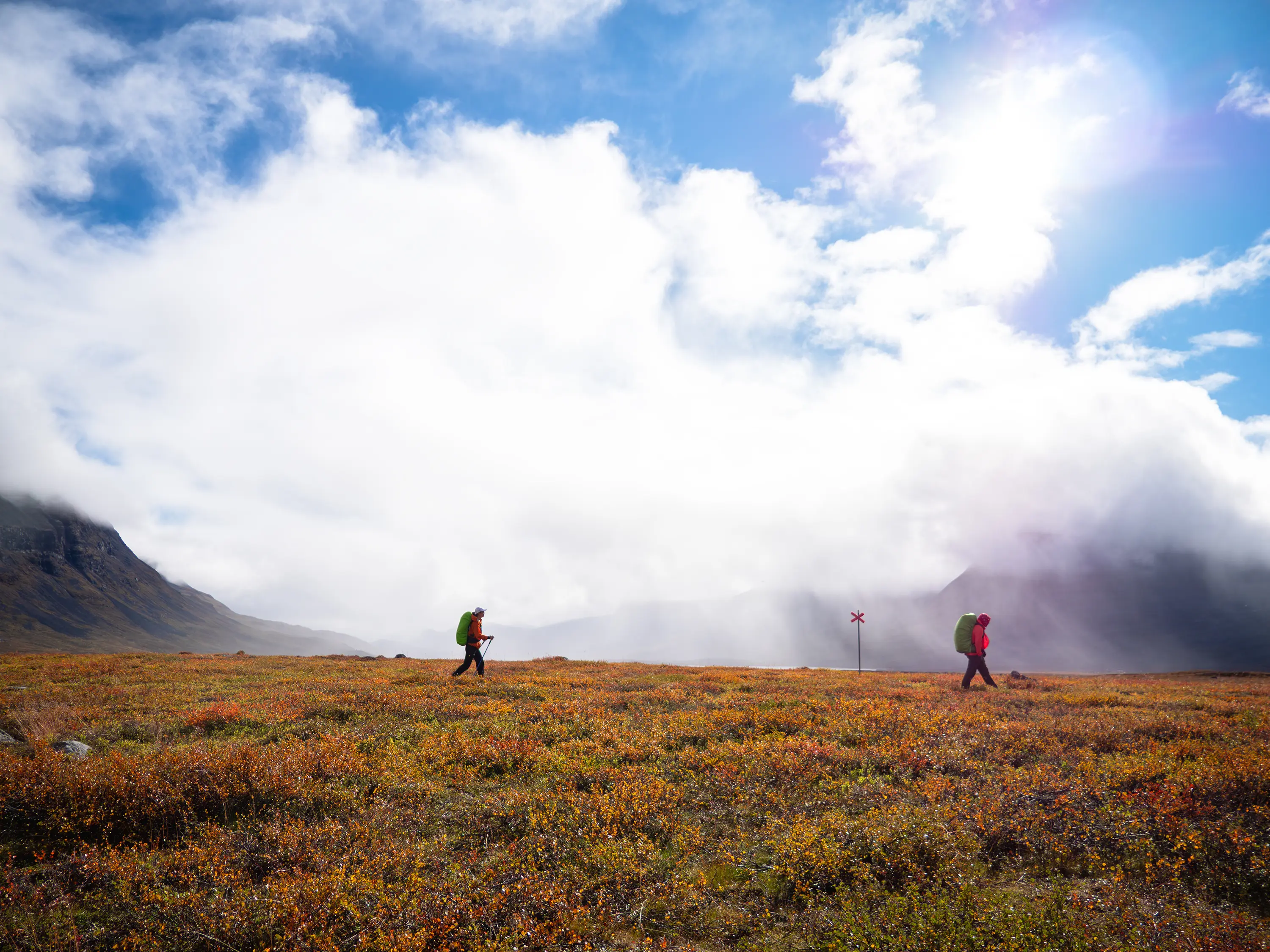 Um poste com X vermelho marca a rota de inverno da Kungsleden e permanece visível na paisagem de outono.