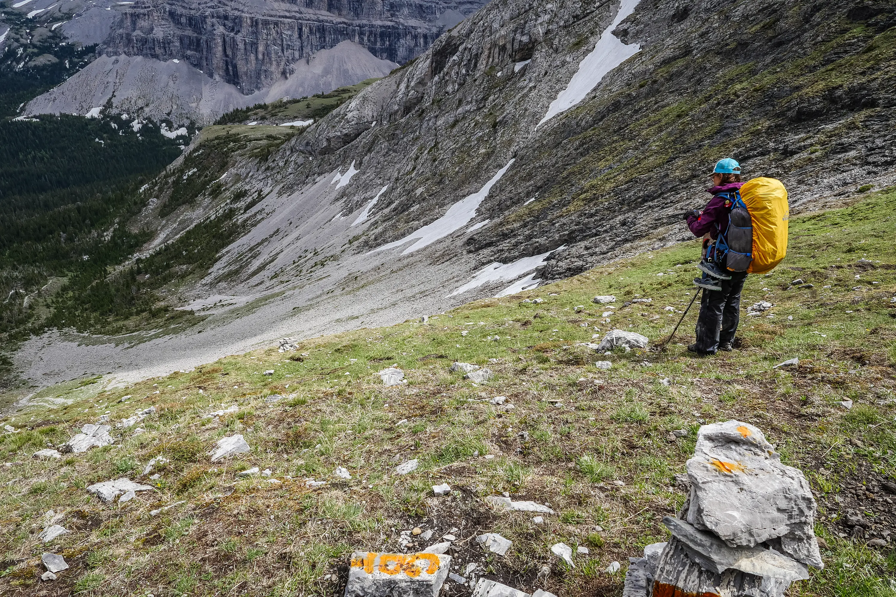 Um monte de pedras com marcação laranja ajuda a orientar o caminho em um trecho aberto das Rocky Mountains canadenses.